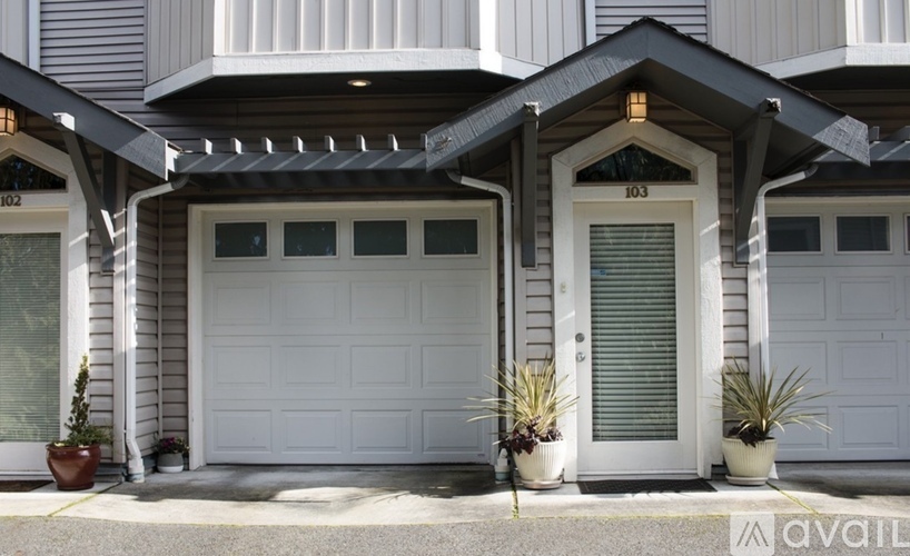 A house with a white garage door and a white door with a window above it.
