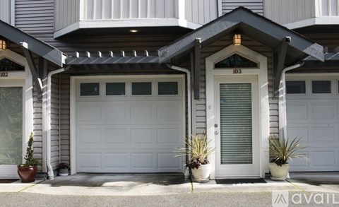 A house with a white garage door and a white door with a window above it.