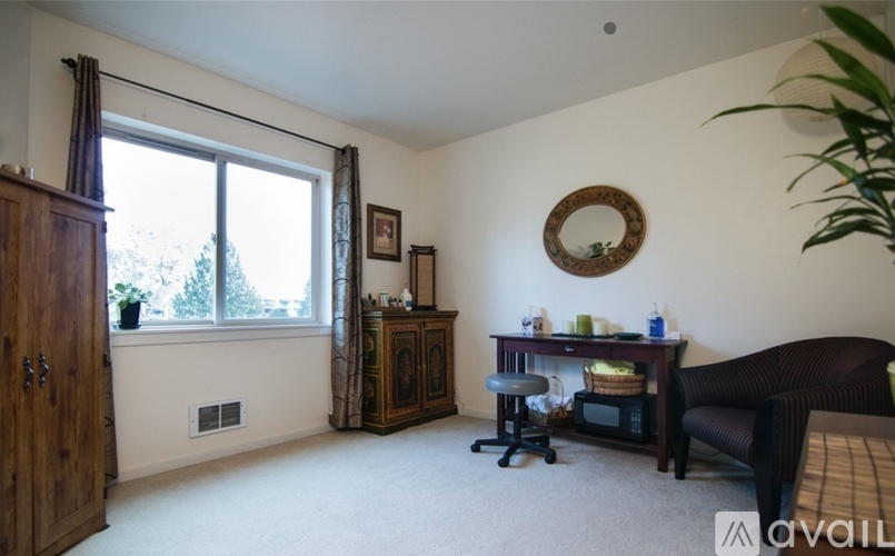 A living room with a brown couch, a wooden cabinet, a small table, and a window with curtains.