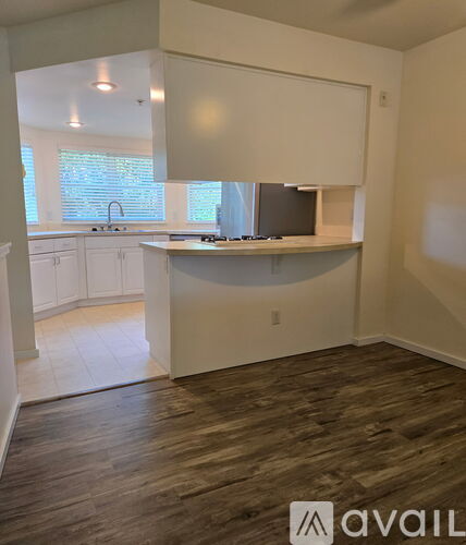 A kitchen with white cabinets and a wooden floor.