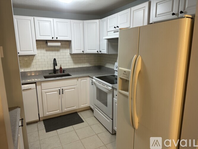 A kitchen with white cabinets and a stainless steel refrigerator.
