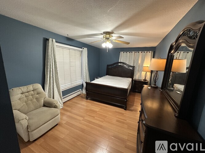 A bedroom with a bed, chair, and dresser.