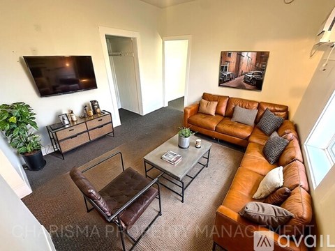 A living room with a brown leather couch and a glass coffee table.