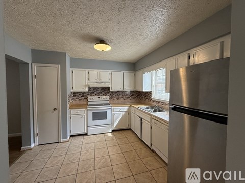A kitchen with a stove, sink, and refrigerator.