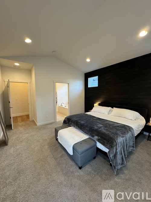 A bedroom with a large bed and a grey carpet.