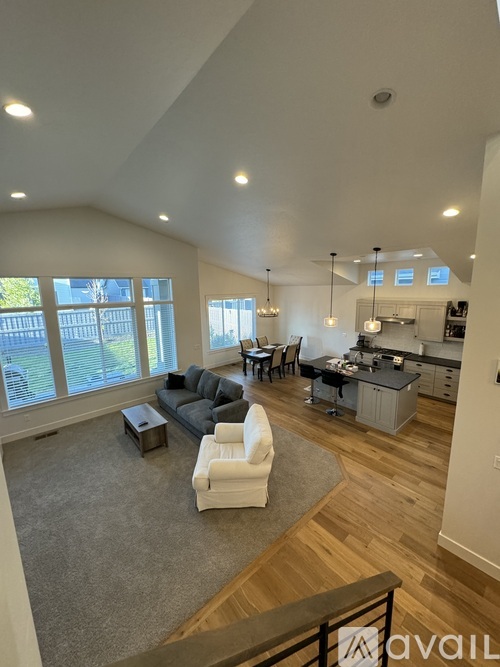 A spacious living room with a grey sofa and a white armchair.
