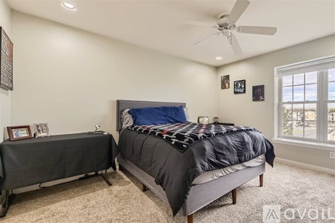 A bedroom with a large bed and a smaller bed with a table in front of it.