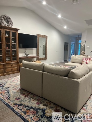 A living room with a beige couch and a wooden cabinet.