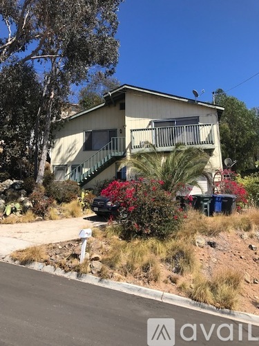 A house with a balcony and a car parked in front.