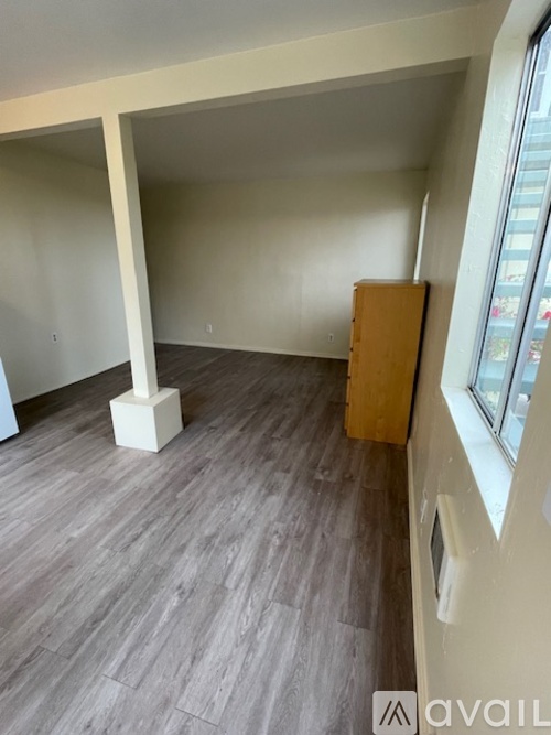 A room with wooden flooring and a white column.