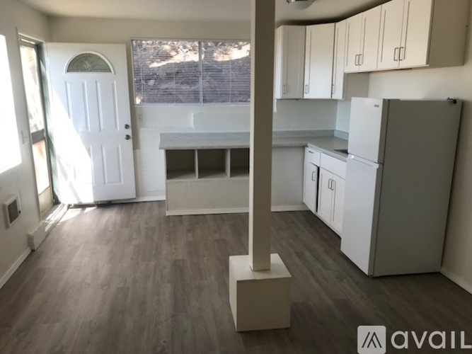 A kitchen with white cabinets and a wooden floor.