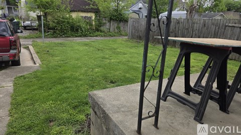 A black metal stand with a wooden top is in the foreground of a grassy area.