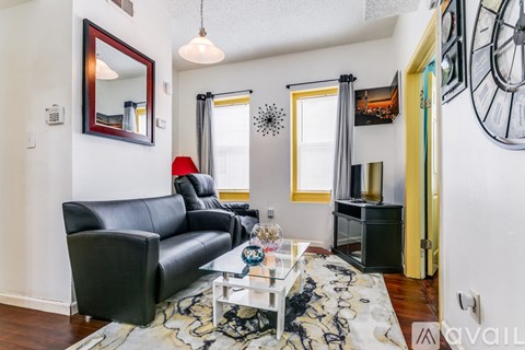 A living room with a black leather couch and a glass coffee table.