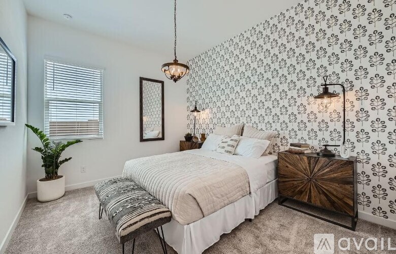 A bedroom with a bed, a bench, and a wallpapered wall.