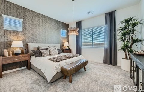 A bedroom with a large bed, a bench, and a potted plant.