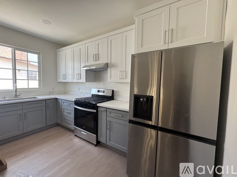 A kitchen with a stainless steel refrigerator and wooden flooring.