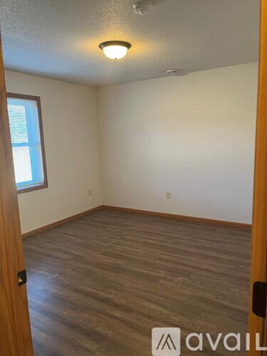 A room with wooden flooring and a window on the left side.