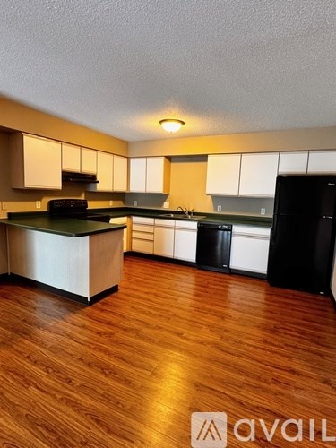 A kitchen with wooden floors and white cabinets.