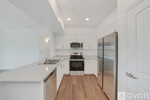 A modern kitchen with white cabinets and a wooden floor.