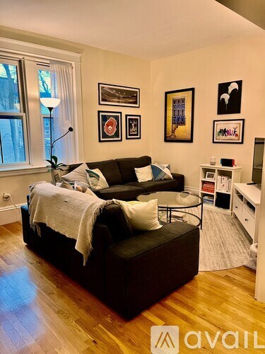 A living room with a black couch and wooden floors.