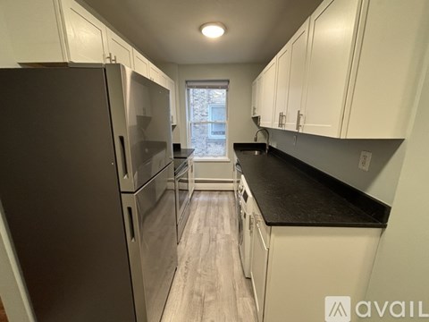 A kitchen with white cabinets and a black countertop.