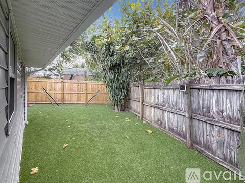 A backyard with a wooden fence and a green lawn.