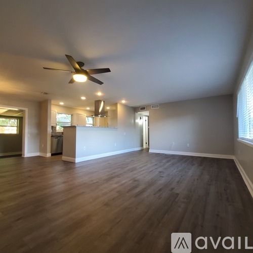 A spacious room with wooden flooring and a ceiling fan.
