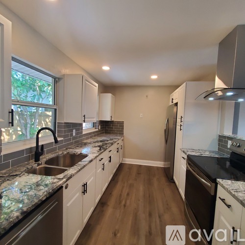 A kitchen with white cabinets and a marble countertop.