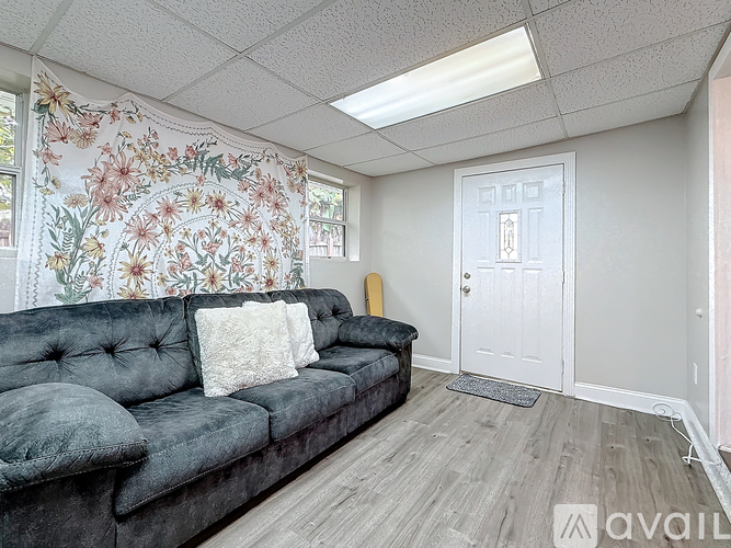 A living room with a grey couch and floral wallpaper.