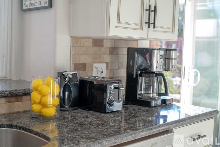 A kitchen counter with a bowl of lemons, a toaster, a coffee maker, and a microwave.