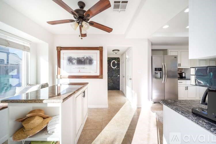 A kitchen with a ceiling fan and a framed picture on the wall.