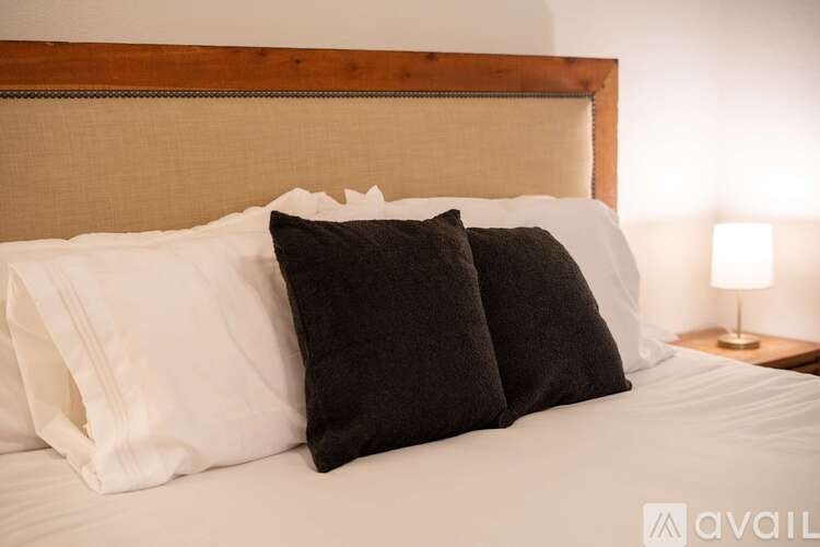 A bed with two pillows and a lamp on a nightstand.