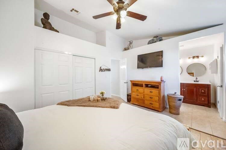 A bedroom with a bed, dresser, and ceiling fan.