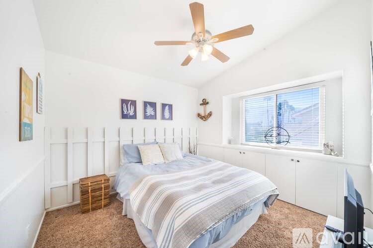 A bedroom with a bed, a ceiling fan, and a window with blinds.