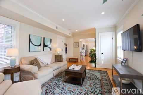 A living room with a white couch and a rug with a pattern on it.