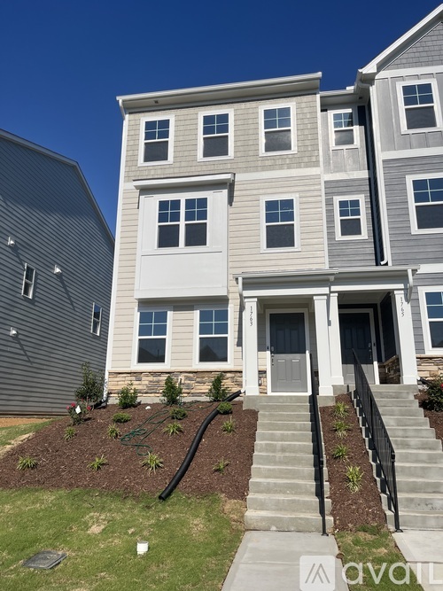 A grey and white two story apartment building with a black railing on the stairs.