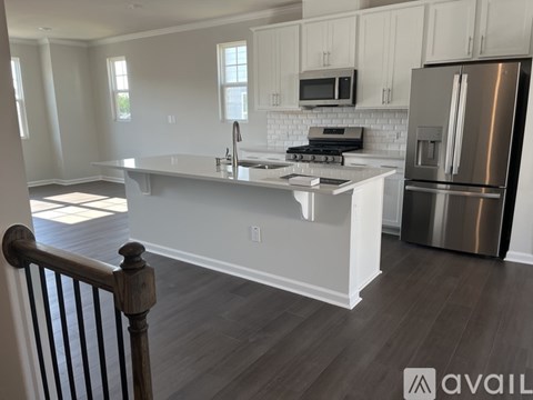 A kitchen with white cabinets and a stainless steel refrigerator.