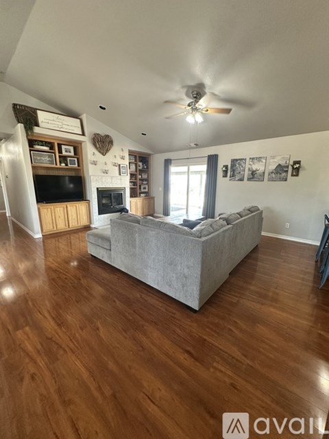 A living room with a grey couch and wooden floors.