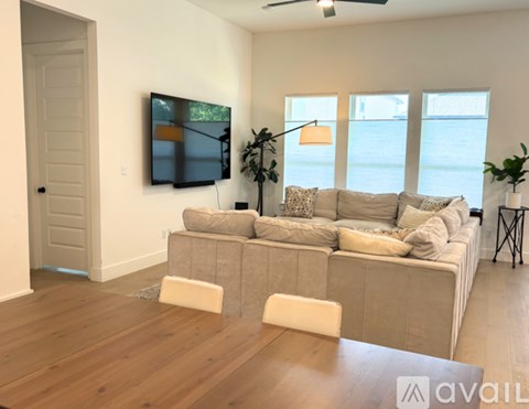 A living room with a grey couch, a wooden floor, and a painting on the wall.