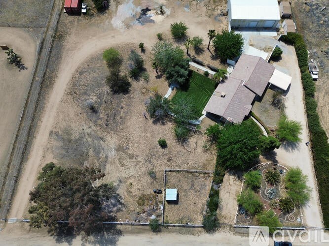 A house with a brown roof is surrounded by trees and bushes.