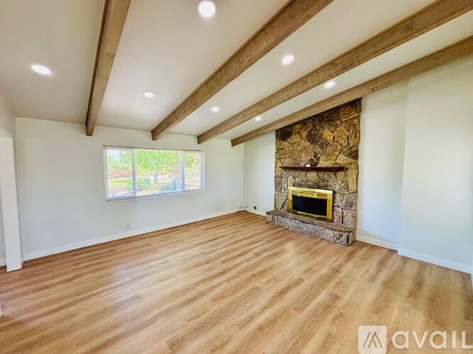 A spacious room with wooden floors and a stone fireplace.