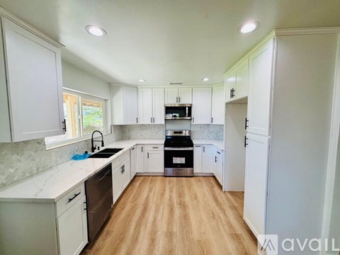 A kitchen with white cabinets and a wooden floor.