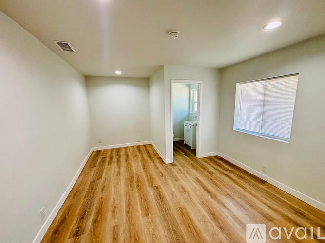 A room with wooden flooring and a window with blinds.