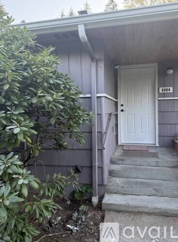 A house numbered 8984 has a white door and steps leading up to it.