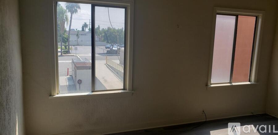 A room with two windows overlooking a street.