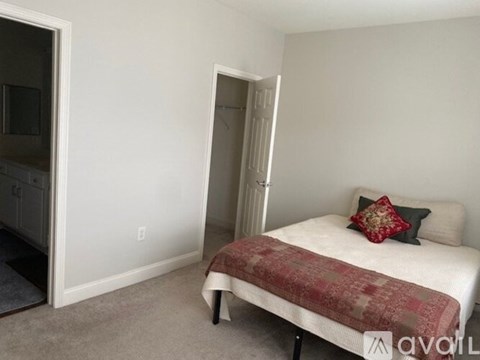 A bedroom with a bed and a doorway leading to a kitchen.