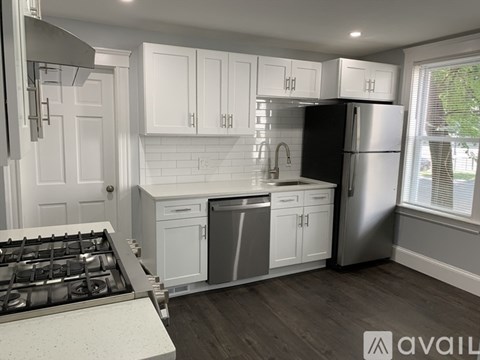 A kitchen with white cabinets and a black refrigerator.