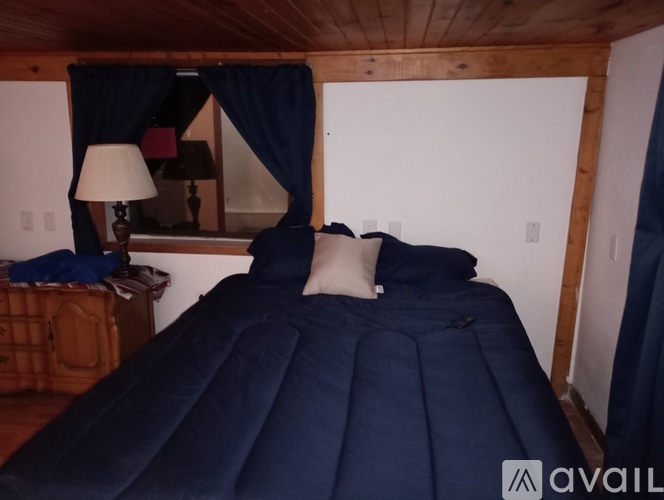 A bed with a blue cover and two pillows is in the image.