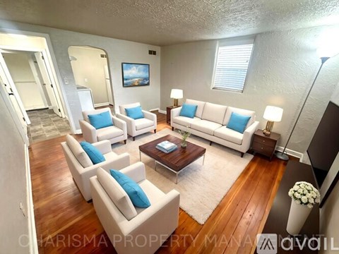A living room with white furniture and a painting on the wall.