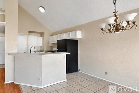 A kitchen with a white counter and black fridge.